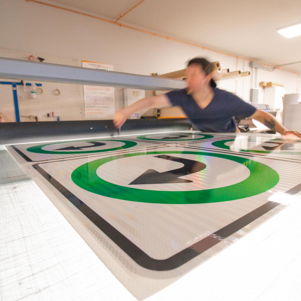 person cutting spec signs on a vinyl cutting table directional arrows
