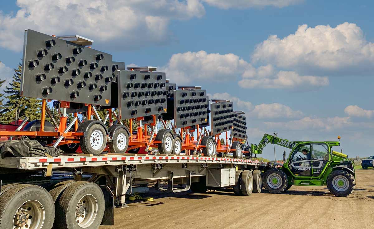 arrow board trailers being unloaded to by a green forklift in Edmonton, Alberta. There are four arrow board trailers. 